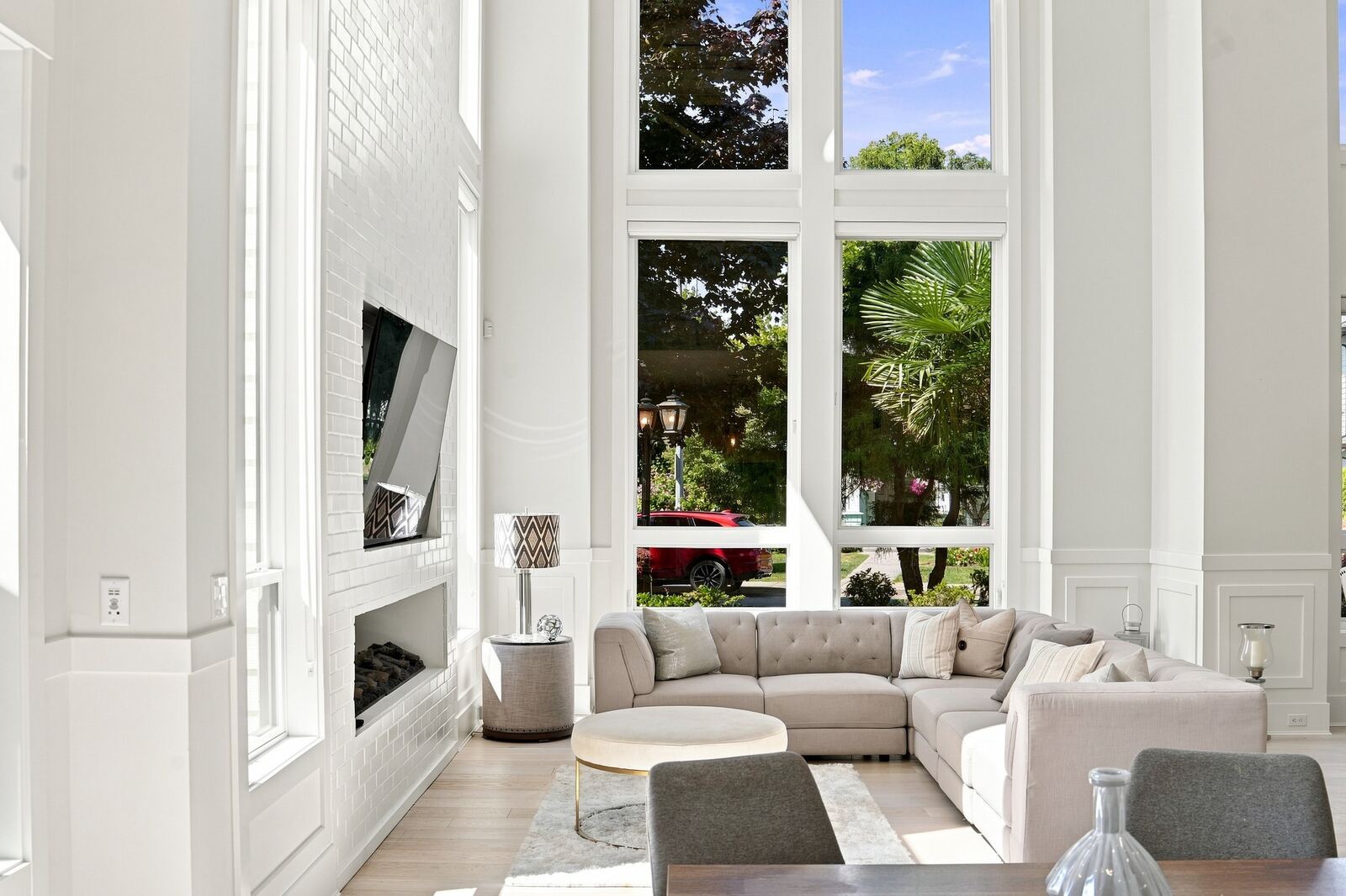 Living room with a cream sectional sofa, fireplace and tall windows looking out to greenery